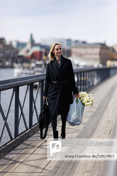Woman walking with daffodils in shopping bag