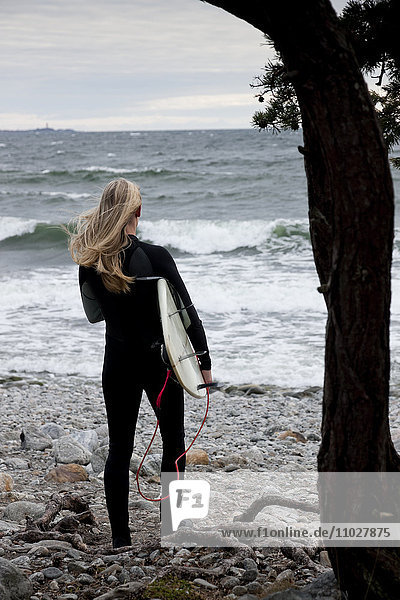 Frau mit Surfbrett am Strand