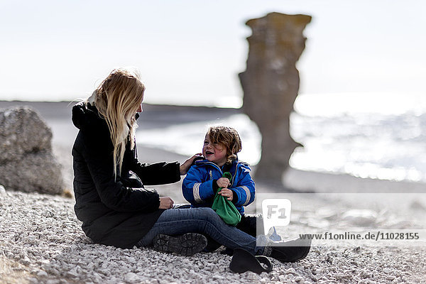 Mutter und Sohn sitzen am Strand