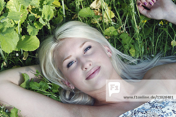 Lächelnde junge Frau im Gras liegend