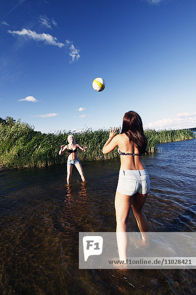 Frauen spielen Volleyball am Wasser