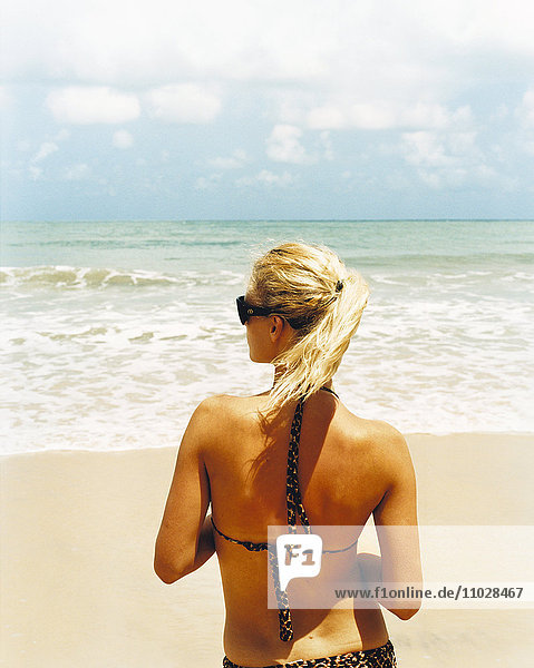 A woman standing on a sandy beach.
