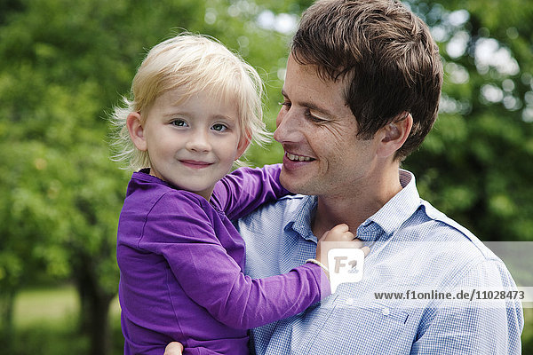 Vater umarmt Tochter im Garten