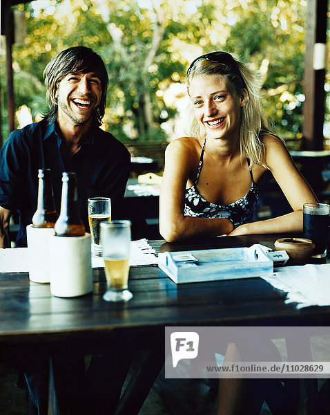 Ein lachender junger Mann und eine lachende Frau in einem Straßencafé.