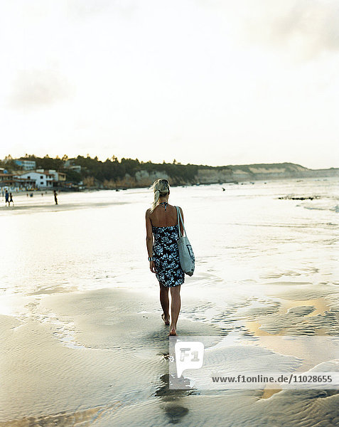 Woman walking barefoot on the beach.