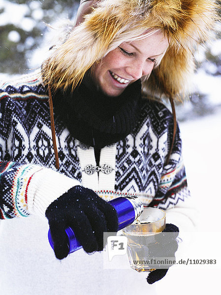 A woman pouring warm wine in a glass.
