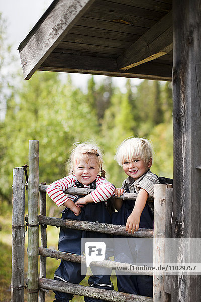 Boy and girl behind wooden fence