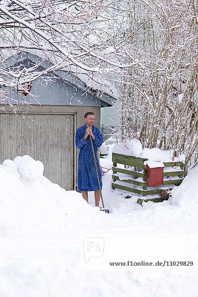 Mann im Bademantel im verschneiten Hinterhof stehend