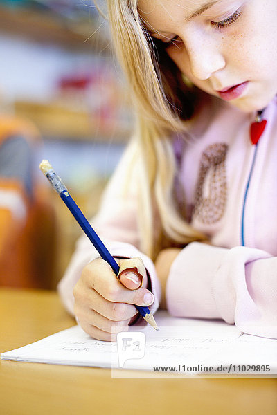 Schulmädchen schreibt auf Papier