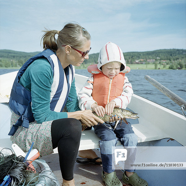 Mutter mit Sohn auf Boot mit Fisch