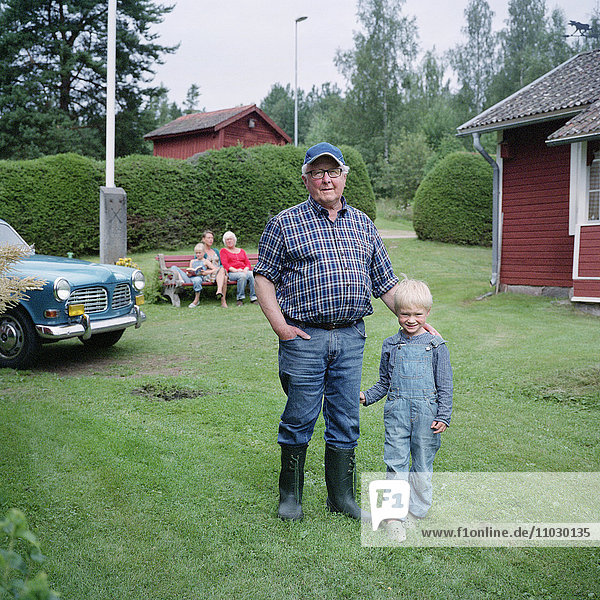 Senior man standing with grandson children in background