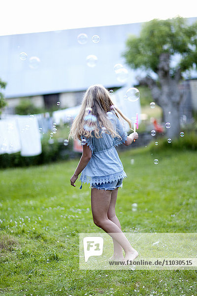 Teenage girl making bubbles in garden