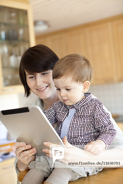 Mutter zeigt ihrem kleinen Sohn ein digitales Tablet