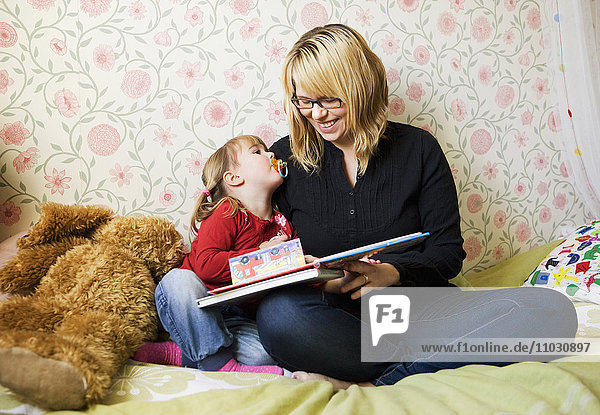 Mother reading book to her daughter