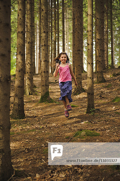 Mädchen läuft und spielt im Wald