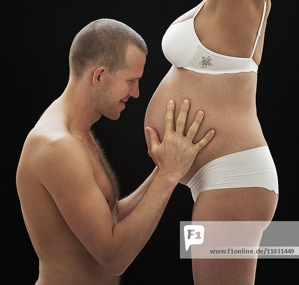 Mann hält schwangeren Frauen Bauch