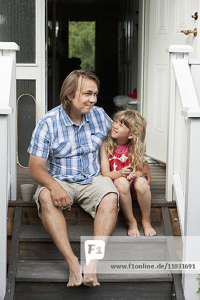 Vater mit Tochter sitzt auf den Stufen vor dem Haus  Sollentuna  Stockholm  Schweden