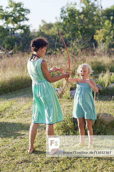 Mother and daughter playing with bow and arrow