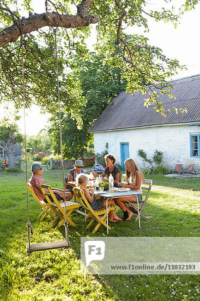 Family dining at outdoor table in garden