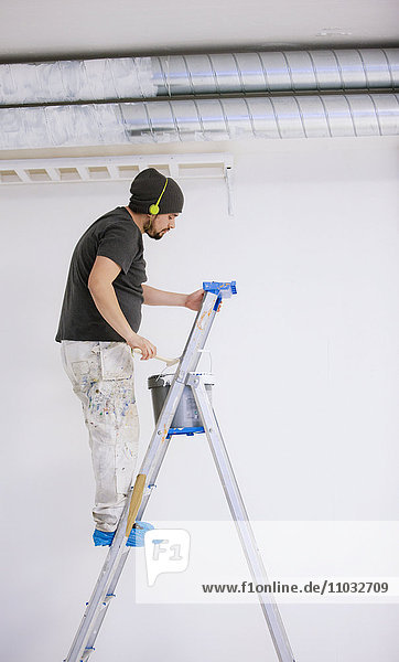 Maler auf einer Leiter mit Kopfhörern  Schweden