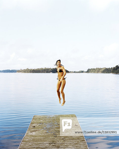 Eine junge Frau springt ins Wasser.