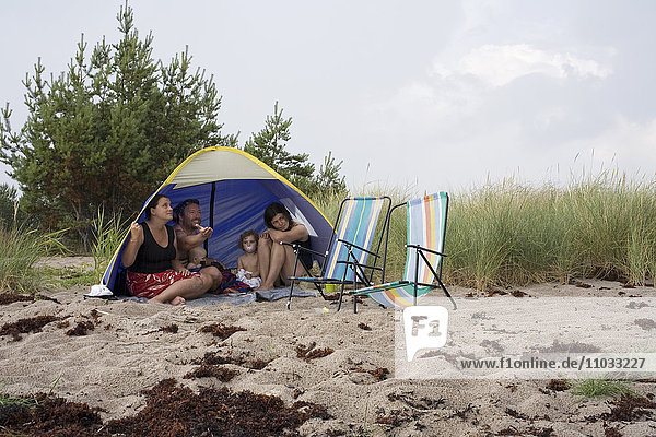 A family in a tent on a beach.