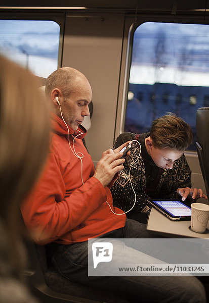 Mann und Jugendlicher benutzen Tablet im Zug