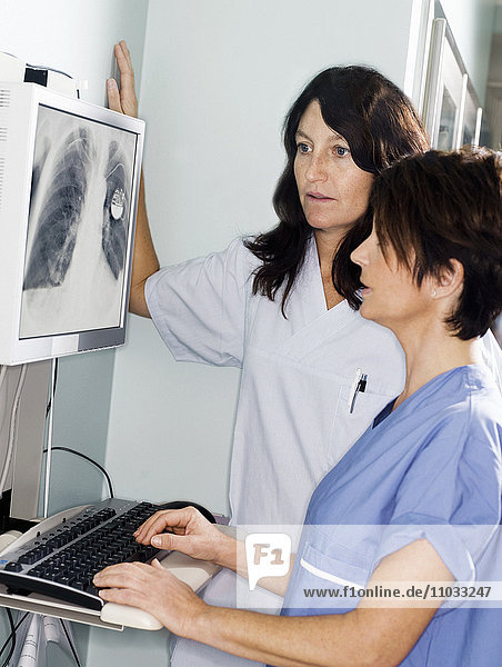 Ein Arzt und eine Krankenschwester sehen sich ein Röntgenbild an.