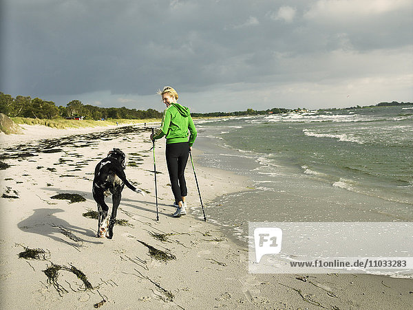 Eine Frau und ein Hund am Strand.