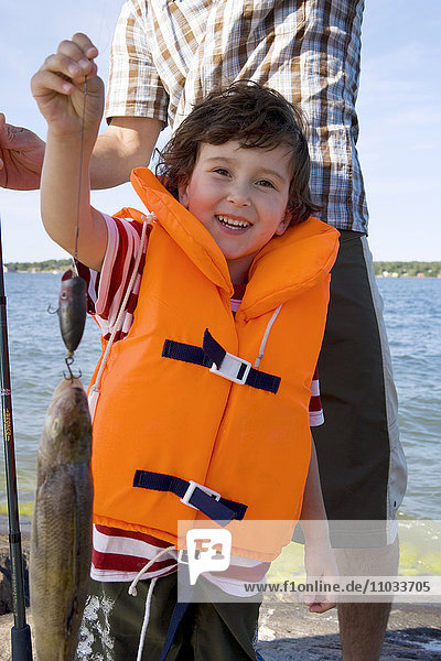 Ein Junge mit einem gefangenen Fisch.
