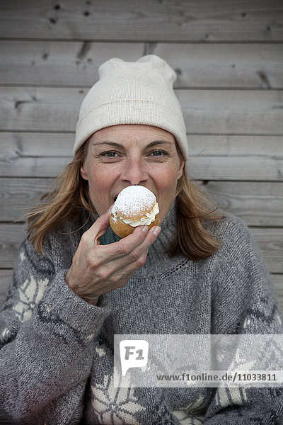Porträt einer Frau in warmer Kleidung  die Kuchen isst