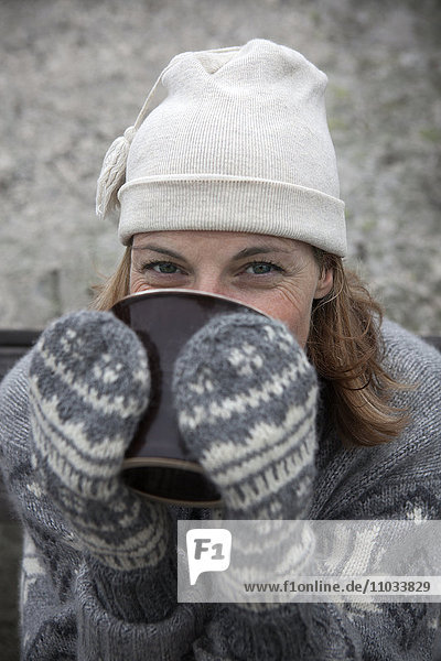 Portrait of woman wearing warm clothing drinking hot drink