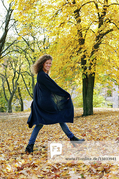 Smiling woman walking in autumn park