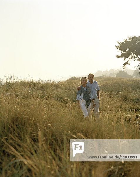 Couple walking together through meadow