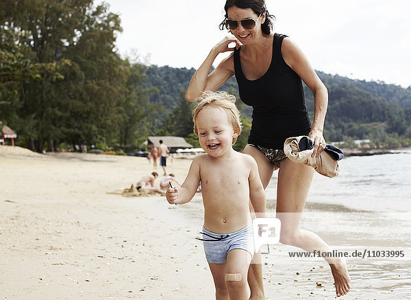 Mutter läuft mit Sohn am Strand