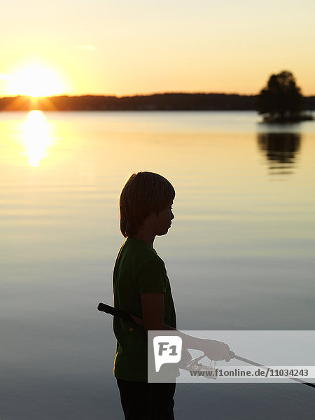 Boy fishing on sea at dusk