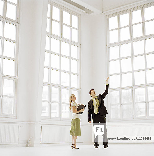 Ein Mann und eine Frau in einem großen leeren Raum mit Fenstern.