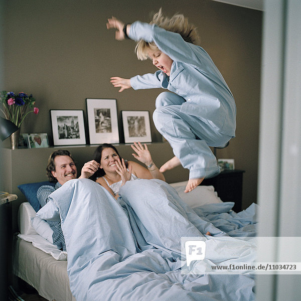 Der Sohn springt ins Bett  wo sich die Eltern entspannen  Hammarby Sjostad  Schweden.