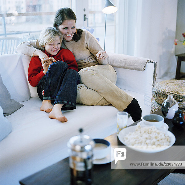 Skandinavische Familie sitzt auf einem Sofa und sieht fern  Hammarby Sjostad  Schweden.