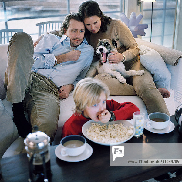 Skandinavische Familie sitzt auf einem Sofa und sieht fern  Hammarby Sjostad  Schweden.