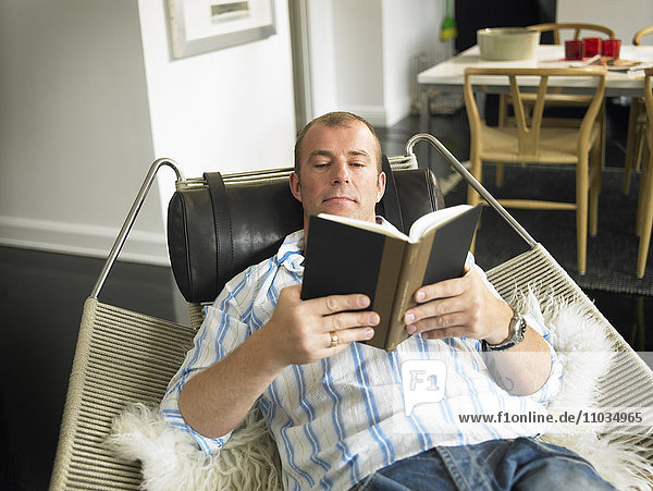 Ein Mann liest in einem Sessel.