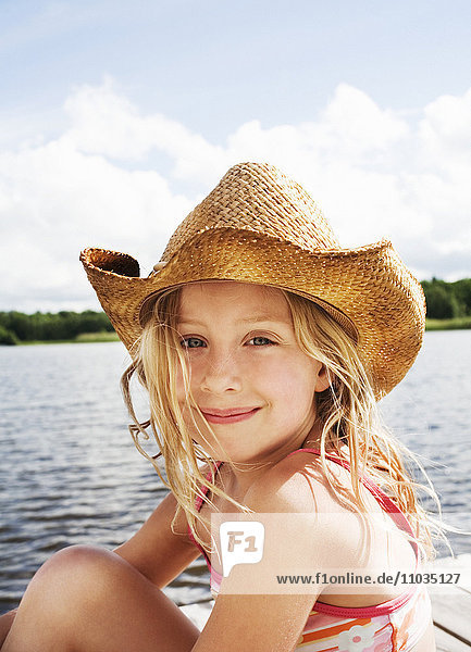 Ein lächelndes Mädchen mit einem Hut auf einem Steg  Schweden.