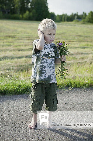 Boy holding wildflowers bouquet on road