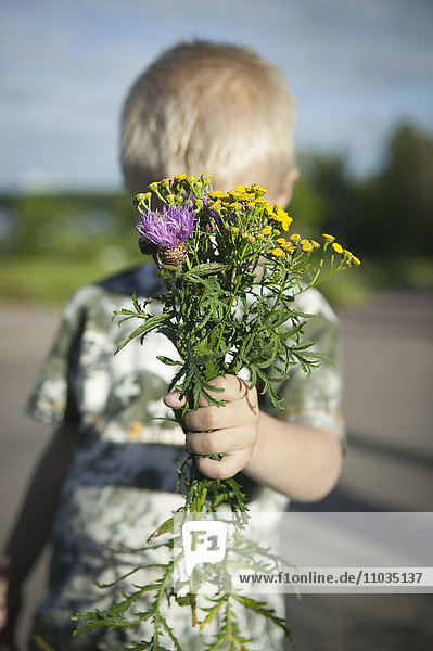 Boy holding wildflowers bouquet