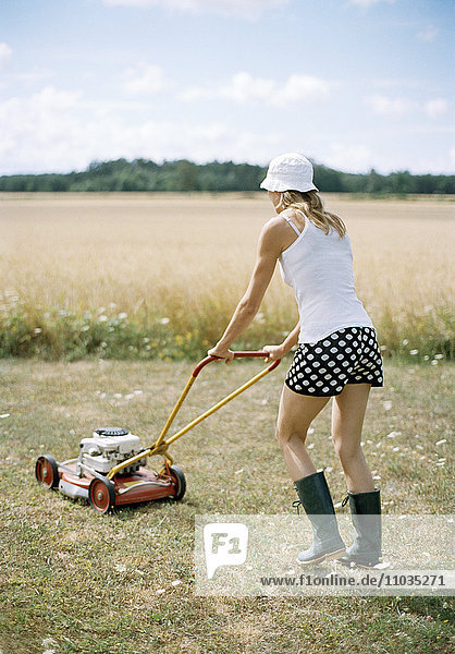Eine Frau mit einem Rasenmäher.