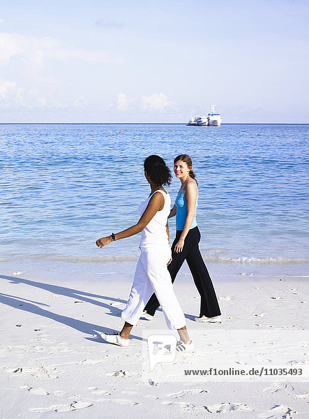 Zwei Frauen  die an einem Strand spazieren gehen.
