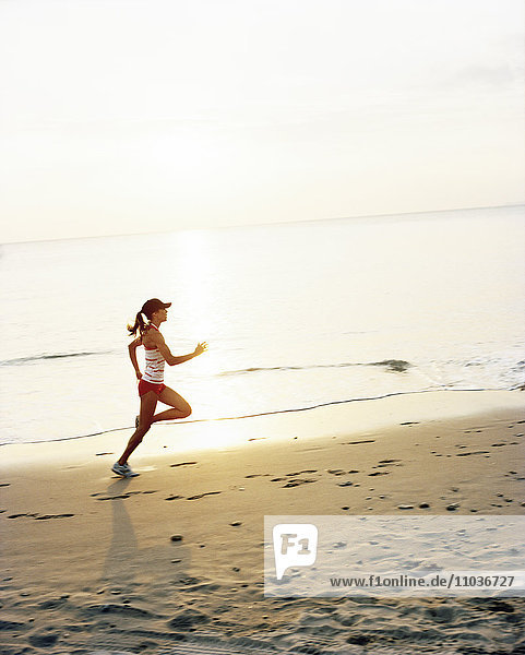 A woman jogging on a beach.
