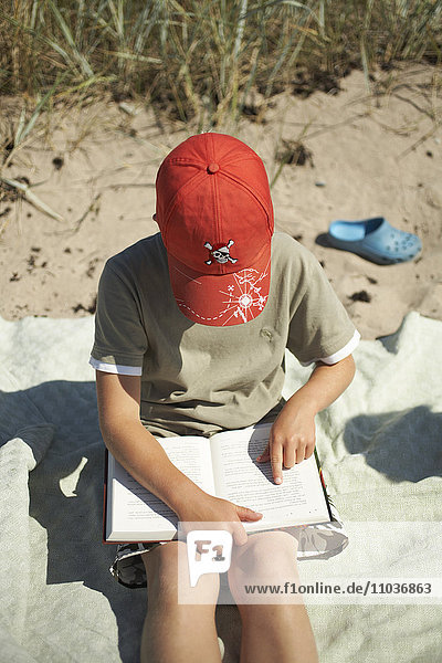 Ein Junge am Strand  der ein Buch liest  Schweden.