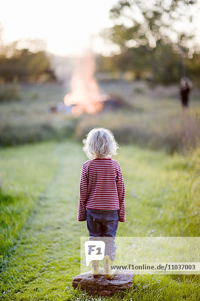 Ein blondes Mädchen vor einem Feuer  Schweden.