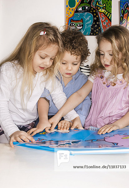 Drei Kinder mit einem Bilderbuch  Schweden.
